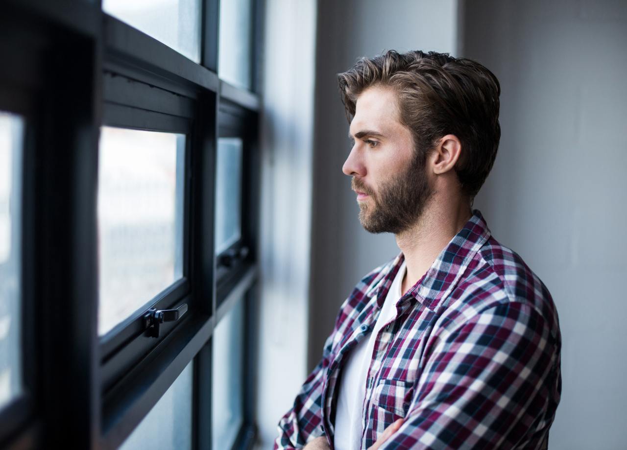 Ursachen für Erektionsprobleme trauriger Mann sieht aus dem Fenster
